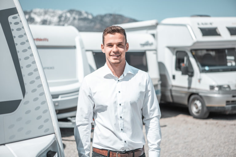 Mitarbeiter von SimplyCamp vor Wohnmobilen und Wohnwagen